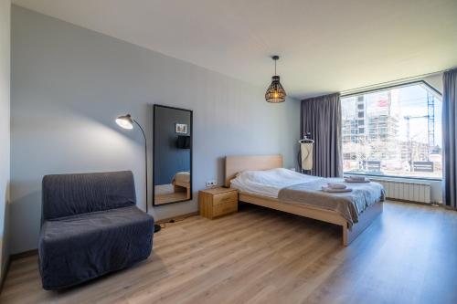 a bedroom with a bed and a chair and a window at Arcadia Apartment, Park and Parking in Sofia