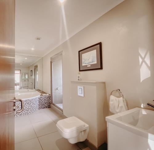 uma casa de banho com uma banheira, um WC e um lavatório. em Sunset Villa em Langebaan