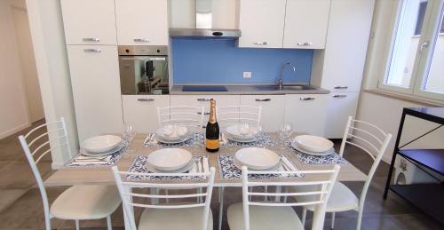 una mesa de comedor con sillas blancas y una botella de vino en Lux Family Apartment, en Bardolino