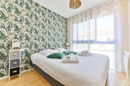 a bedroom with a bed with a green and white wallpaper at Appartement cosy, idéalement situé en centre-ville in Les Sables-d'Olonne