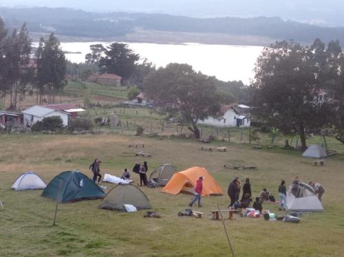 a group of people in a field with tents at Camping Las Acacias in Guatavita