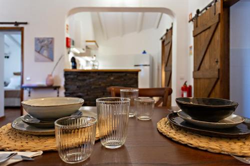 una mesa de madera con tazones y vasos. en Casa da Soalheira, en São Brás de Alportel