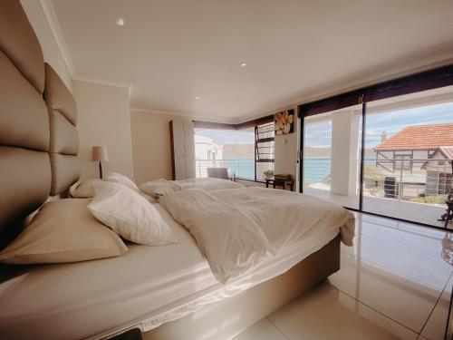 a bedroom with a large bed and a large window at Sunset Cottage in Langebaan