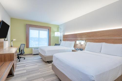 a hotel room with two beds and a flat screen tv at Holiday Inn Express & Suites St. Louis - Chesterfield by IHG in Chesterfield