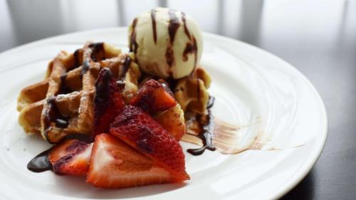 a white plate with waffles and ice cream and strawberries at Holiday Inn Parramatta by IHG in Sydney