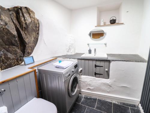 a bathroom with a washing machine and a sink at Cwm Yr Afon Mawr in Llanbedr