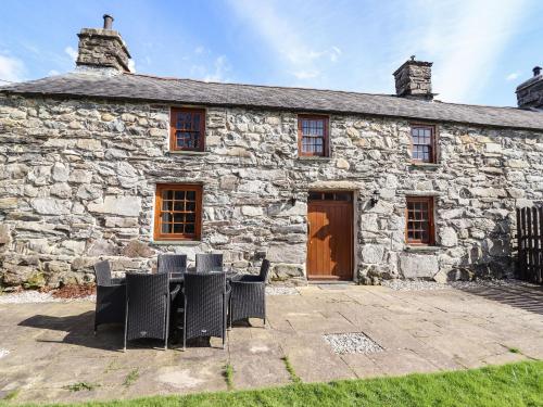 an old stone building with chairs in front of it at Cwm Yr Afon Mawr in Llanbedr