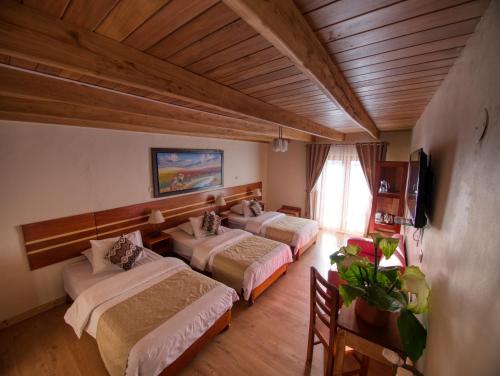 a hotel room with three beds and a television at Sol Ollantay Boutique Hotel in Ollantaytambo