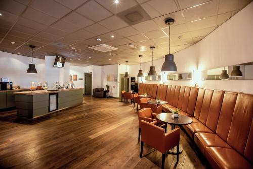 ユトレヒトにあるLeonardo Hotel Utrecht City Centerの椅子とテーブルとバーのあるレストラン
