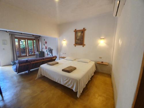 a bedroom with a white bed and a couch at LUNA DE MIEL con aire acondicionado in Mazunte