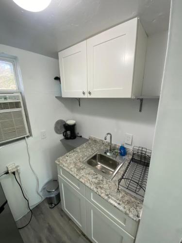 a kitchen with white cabinets and a sink at Uptown Inn & Suites in St Petersburg