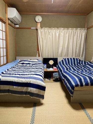 高山市にあるゲストハウス「日の出」のベッドルーム1室(ベッド2台、壁掛け時計付)