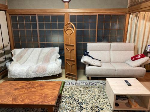 a living room with a couch and a chair at Guest House Hinode in Takayama