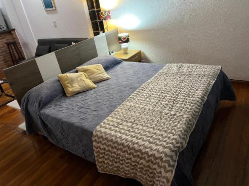 1 dormitorio con 1 cama con manta azul y almohadas amarillas en Departamento tipo Loft en Balvanera en Buenos Aires