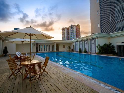 uma piscina com mesas e cadeiras e um guarda-sol em Zhuhai Charming Holiday Hotel-Free Welcome Fruit Plate em Zhuhai