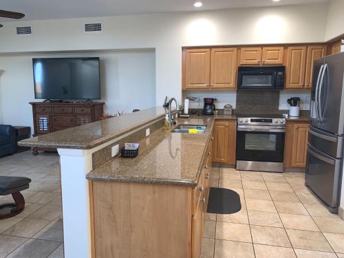 a kitchen with wooden cabinets and a large counter top at The Best 3bd 3ba Condo Near Ocean with AC Office and Loft ACJ1 in Kailua-Kona