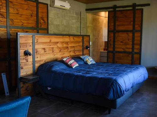 Schlafzimmer mit einem großen Bett mit einem Kopfteil aus Holz in der Unterkunft Mahuida Lodge Valle de Uco in Colonia Las Rosas