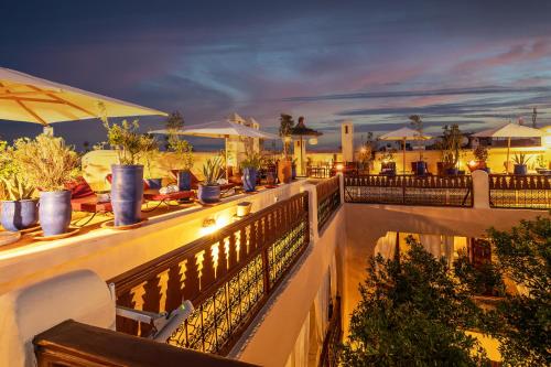 a balcony of a resort with tables and chairs at Riad Dar El Médina - Heated Swimming pool, jacuzzi & Spa in Marrakech