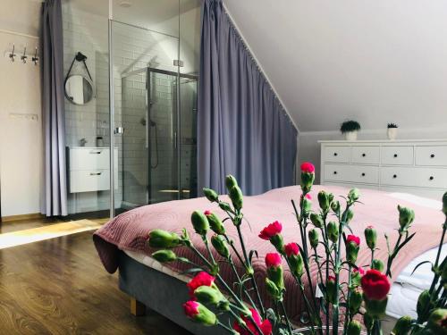 a bedroom with a bed and a shower with red flowers at Saskia Dwór & Spa Willa z basenem in Podmacharce