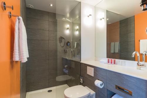 een badkamer met een douche, een toilet en een wastafel bij Leonardo Hotel Amsterdam Rembrandtpark in Amsterdam