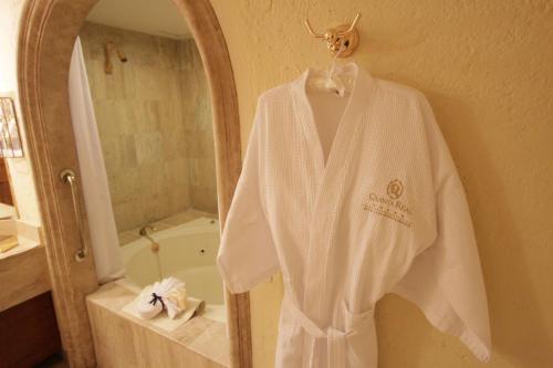 a white robe hanging on a wall in a bathroom at Quinta Real Zacatecas in Zacatecas