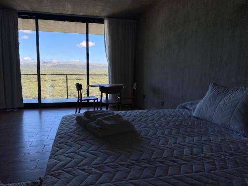 a bedroom with a bed and a large window with a view at Casa Sol in Villa Cura Brochero