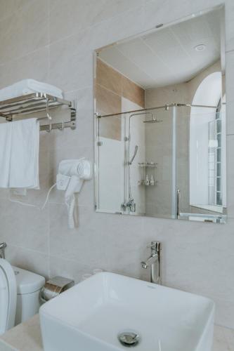 a white bathroom with a sink and a mirror at Le Cactus Hotel Ha Long in Ha Long