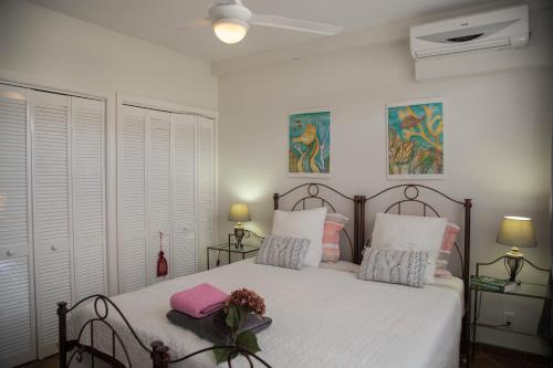 a bedroom with a bed with white sheets and pink pillows at Casa Curacao Ocean Resort near Mambo Beach in Willemstad
