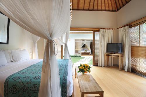 a bedroom with a bed and a tv in it at Villa Bali Asri Batubelig in Seminyak