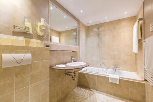 a bathroom with a sink and a bath tub at Leonardo Hotel Antwerp The Plaza in Antwerp