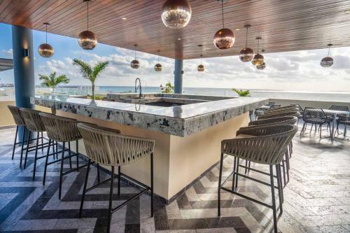 - un bar avec des chaises et un comptoir offrant une vue sur l'océan dans l'établissement Singular by Andiani Travel, à Playa del Carmen