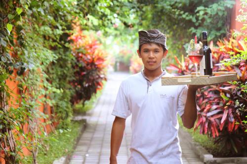 a young man holding a tray with a trophy at Villa Bali Asri Batubelig in Seminyak