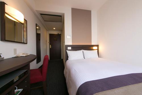 京都市にあるアーバンホテル京都のベッドと赤い椅子が備わるホテルルームです。