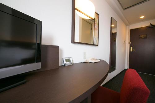 a room with a large television and a red chair at Urban Hotel Kyoto in Kyoto