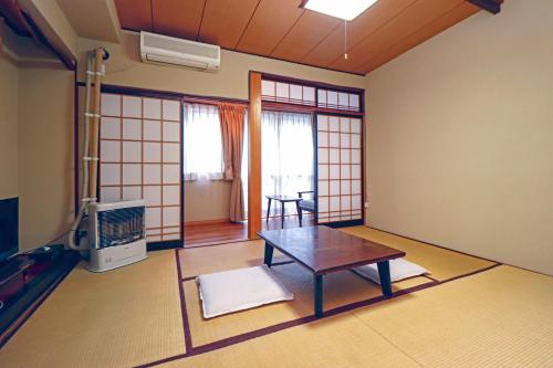 una camera con tavolo e TV di Kobori Ryokan a Hirosaki