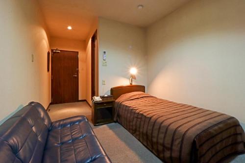 Habitación de hotel con cama y sofá en Kobori Ryokan en Hirosaki
