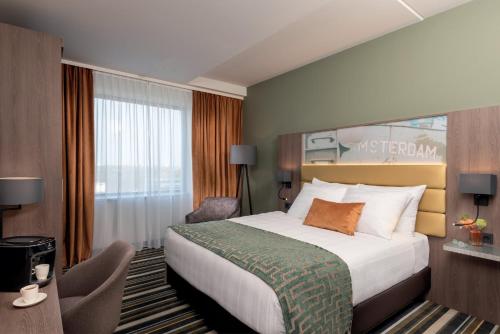 a hotel room with a bed and a window at Leonardo Royal Hotel Amsterdam in Amsterdam