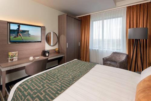 Habitación de hotel con cama, escritorio y TV. en Leonardo Royal Hotel Amsterdam, en Ámsterdam