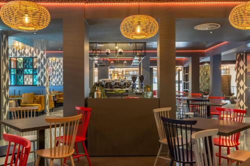 a restaurant with red chairs and tables and a bar at Leonardo Boutique Museumhotel in Amsterdam