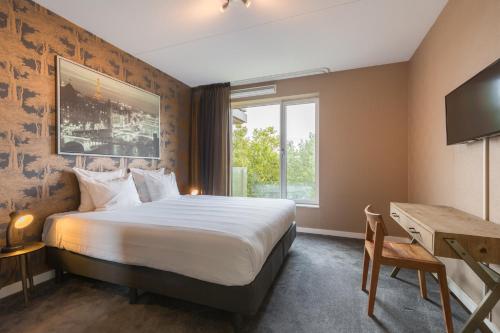 een hotelkamer met een bed, een bureau en een raam bij Leonardo Hotel Papendrecht in Papendrecht