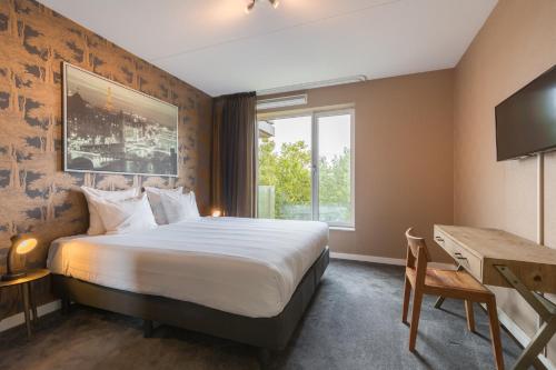 a hotel room with a bed and a desk and a window at Leonardo Hotel Papendrecht in Papendrecht