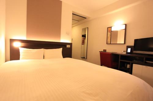 京都市にあるアーバンホテル京都の白いベッドとテレビが備わるホテルルームです。