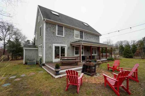 uma casa com cadeiras vermelhas e um grelhador no quintal em Home in Oak Bluffs em Oak Bluffs