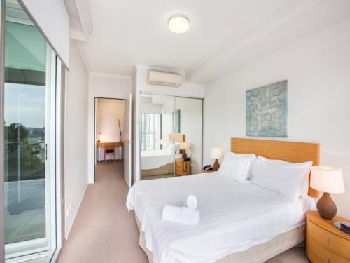 1 dormitorio con 1 cama blanca grande y balcón en Story Apartments, en Brisbane
