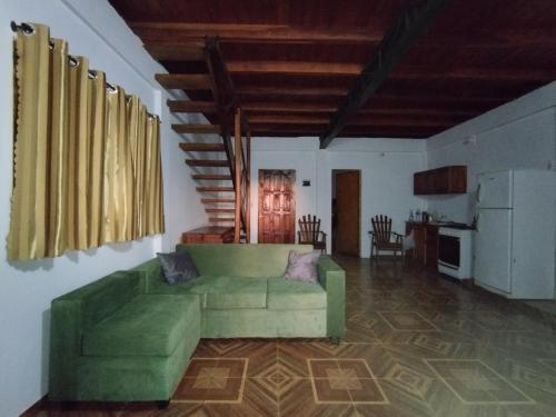 ein Wohnzimmer mit einem grünen Sofa und einer Küche in der Unterkunft A la Vera del Río in Puerto Iguazú