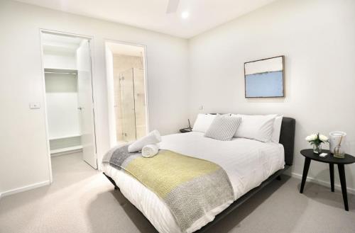 Un dormitorio blanco con una gran cama blanca. en Pinecone Lodge, en Jindabyne