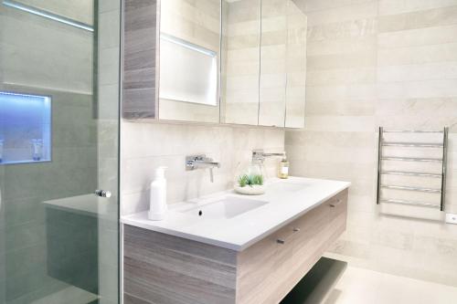 a bathroom with a white sink and a shower at Pinecone Lodge in Jindabyne