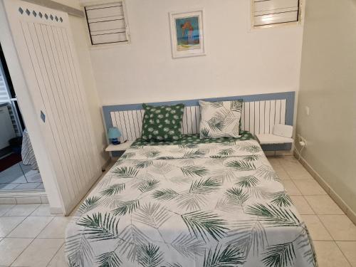 a bedroom with a bed with a green and white comforter at appartement spacieux vue sur mer in La Trinité