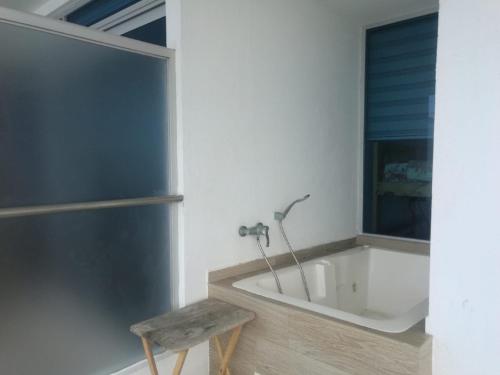 ein Badezimmer mit einer Badewanne und einem Holzhocker in der Unterkunft Apartment (Grand Diamond Beach) Tonsupa in Tonsupa