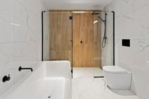 a bathroom with a tub and a toilet and a shower at Clearwater Quays Apartments in Christchurch